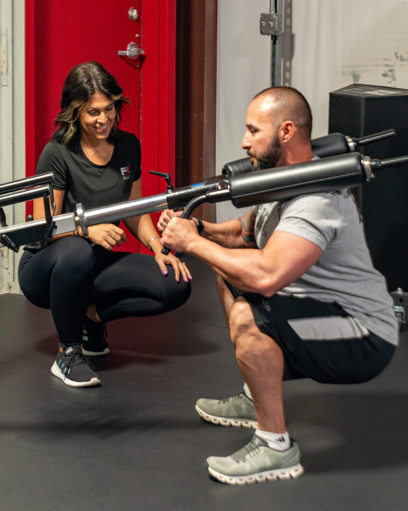 man at weight machine with trainer
